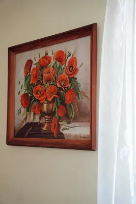 a painting of a vase of flowers on a wall at GP Hostel in Šiauliai
