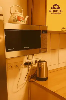 a microwave on top of a refrigerator in a kitchen at GP Hostel in Šiauliai