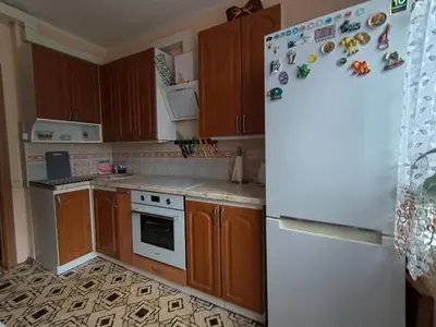 a kitchen with wooden cabinets and a white refrigerator at Weekend Home in Visaginas