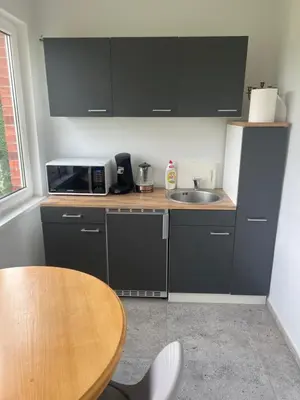 a kitchen with black cabinets and a wooden table at Pušų Sodas in Birštonas