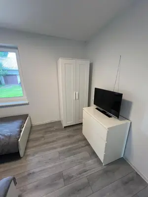a living room with a television on a white cabinet at Pušų Sodas in Birštonas