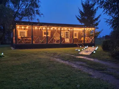 a cabin with lights on it in a yard at night at Sodyba Gluosnis