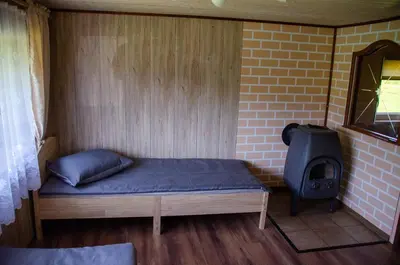 a small room with a bed and a stove at Sodyba Gluosnis