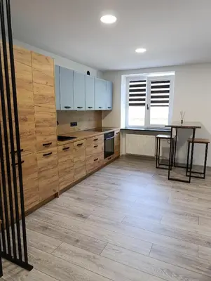 a kitchen with wooden cabinets and a table in it at Alytus Miško studio in Alytus