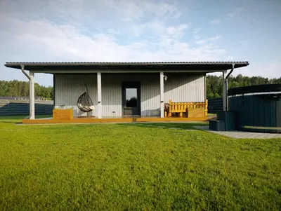a building with a bench and a grass field at Sodyba Miško pakrašty in Gailiūnai
