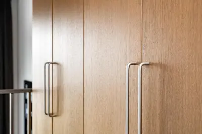a wooden cabinet with two handles in a kitchen at Cinema Loft - Self Check in in Vilnius