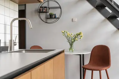 a kitchen with a sink and two chairs and a table at Cinema Loft - Self Check in in Vilnius