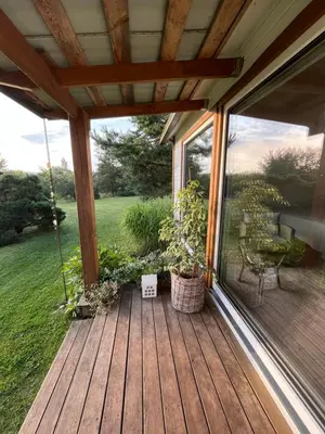 a screened in porch with a swing and a chair at Namelis prie Čiobiškio kelto