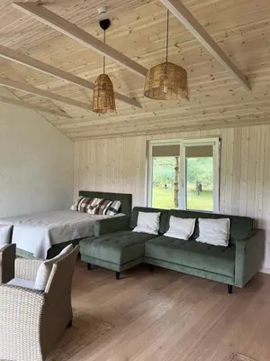 a living room with a bed and a couch and windows at Namelis prie Čiobiškio kelto