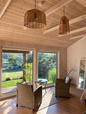 a living room with two chairs and a table and windows at Namelis prie Čiobiškio kelto