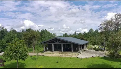 a house with a black roof in a field at Kvapu sodyba