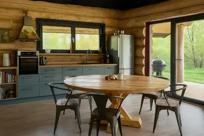 a kitchen with a wooden table and a refrigerator at Kvapu sodyba