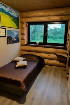 a bedroom with a bed in a log cabin at Kvapu sodyba
