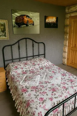 a bedroom with a bed with a floral bedspread and a car at Kvapu sodyba
