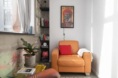 a living room with a orange chair and a picture at Brand-new & Stylish Loft - Hip District Uptown by Reside Baltic in Vilnius