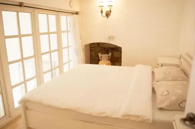 a bedroom with a white bed and a fireplace at Provence Home in Vilnius