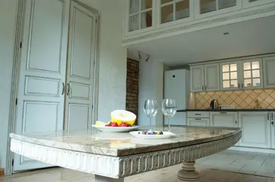 a kitchen with a table with a bowl of fruit and wine glasses at Provence Home in Vilnius