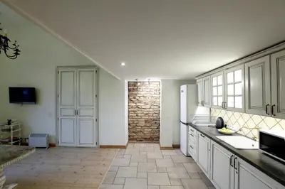 a kitchen with white cabinets and a brick wall at Provence Home in Vilnius