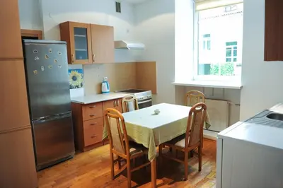 a kitchen with a table with chairs and a refrigerator at Best Location 3 Bedroom Apartment in Vilnius