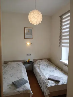 two twin beds in a room with a chandelier at Big apartment in city center in Kaunas
