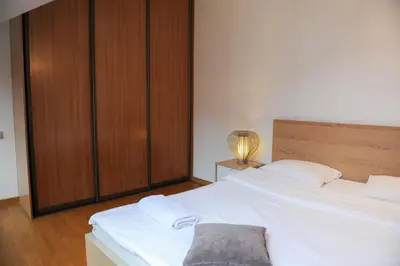 a bedroom with a large white bed and a wooden cabinet at Rooftop Charm Stylish 2BDR Steps from Town Hall in Vilnius