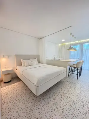 a white bedroom with a bed and a table and chairs at Bright white in Vilnius