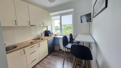 a kitchen with white cabinets and black stools at Virš miesto in Utena