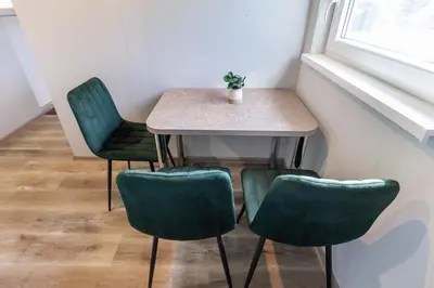 a table with four green chairs and a plant on it at Baba Yaga Treehouse in Meškiai