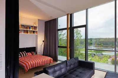 a living room with a couch and large windows at Design apartment with view to Nemunas, Prienai in Pakopi
