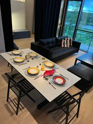 a table in a living room with plates and utensils at Design apartment with view to Nemunas, Prienai in Pakopi