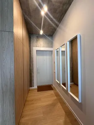a hallway with wood floors and a door with mirrors at Apartamentai prie Soboro in Kaunas