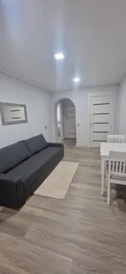 a living room with a black bed and a table at Apartamentai Grigiškes in Grigiškės