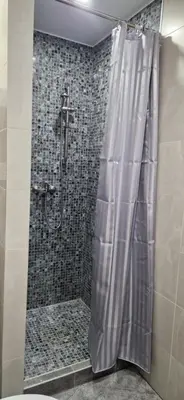 a shower with a shower curtain in a bathroom at Apartamentai Grigiškes in Grigiškės