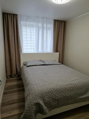 a bedroom with a bed and a window with curtains at Apartamentai Grigiškes in Grigiškės
