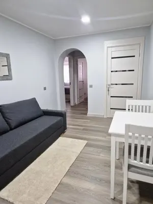a living room with a black couch and a table at Apartamentai Grigiškes in Grigiškės