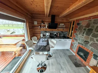 a kitchen with a stone fireplace in a log cabin at Atokvėpis Alantos kaime in Alanta