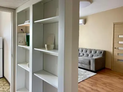 a living room with a gray couch and shelves at Mens Cave in Šiauliai