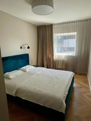 a bedroom with a large bed with a blue headboard and a window at Cashmere apartment in Žaliakalnis in Kaunas