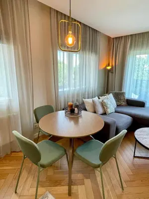 a living room with a couch and a table and chairs at Cashmere apartment in Žaliakalnis in Kaunas