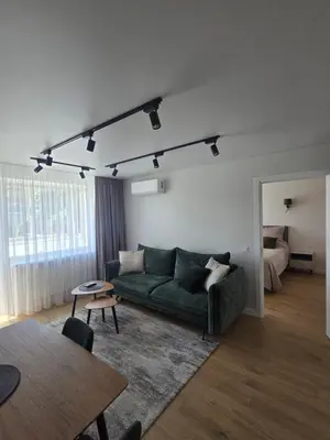 a living room with a green couch and a bed at Central Stay in Šiauliai in Šiauliai