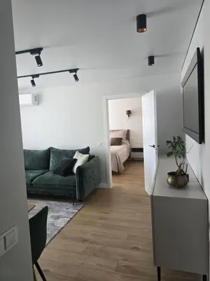 a living room with a green couch and a bed at Central Stay in Šiauliai in Šiauliai