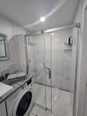 a bathroom with a shower and a washing machine at Central Stay in Šiauliai in Šiauliai