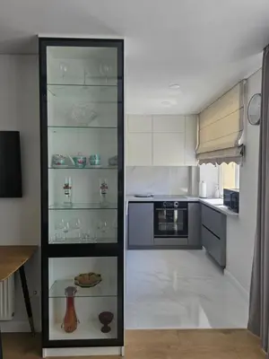 a kitchen with a glass cabinet with dishes in it at Central Stay in Šiauliai in Šiauliai
