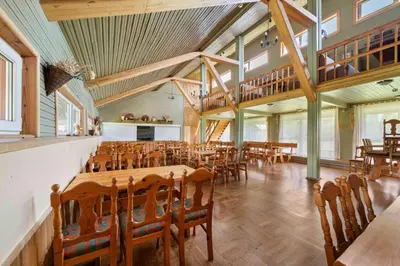 a dining room with wooden tables and chairs at Poilsio kompleksas Tolieja Vieta renginiams bei poilsiui ant ežero kranto in Kulionys
