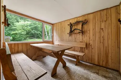 a wooden room with a bench and a table and a window at Poilsio kompleksas Tolieja Vieta renginiams bei poilsiui ant ežero kranto in Kulionys