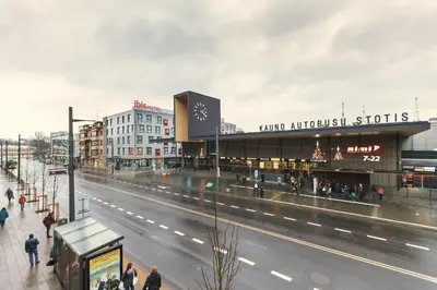 a street with people walking in front of a shopping center at Happy Inn in Kaunas