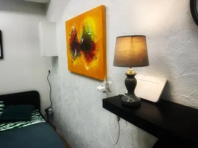 a bedroom with a table with a lamp and a painting at Studio 10 min walk from old town in Vilnius
