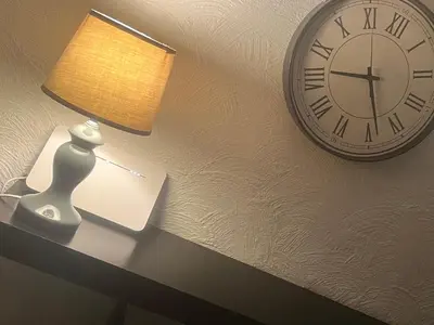 a clock on a wall next to a table with a lamp at Studio 10 min walk from old town in Vilnius