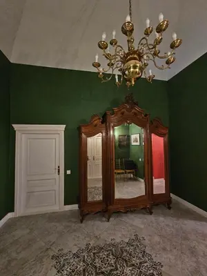 a green room with a mirror and a chandelier at Bistrampolio dvaro Jackaus Vila