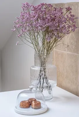 a vase filled with purple flowers next to a plate with donuts at Traku apartament in Pakopi